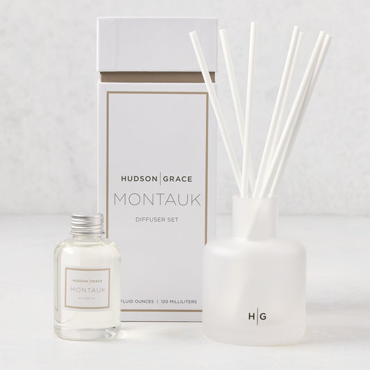 Hudson Grace Montauk Scented Reed Diffuser set: clear glass bottle, frosted glass vessel with white reeds, and white box.