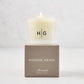 Hudson Grace Montauk Scented Votive candle in a frosted glass vessel with "HG" logo, on a taupe gift box.