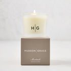 Hudson Grace Montauk Scented Votive candle in a frosted glass vessel with "HG" logo, on a taupe gift box.
