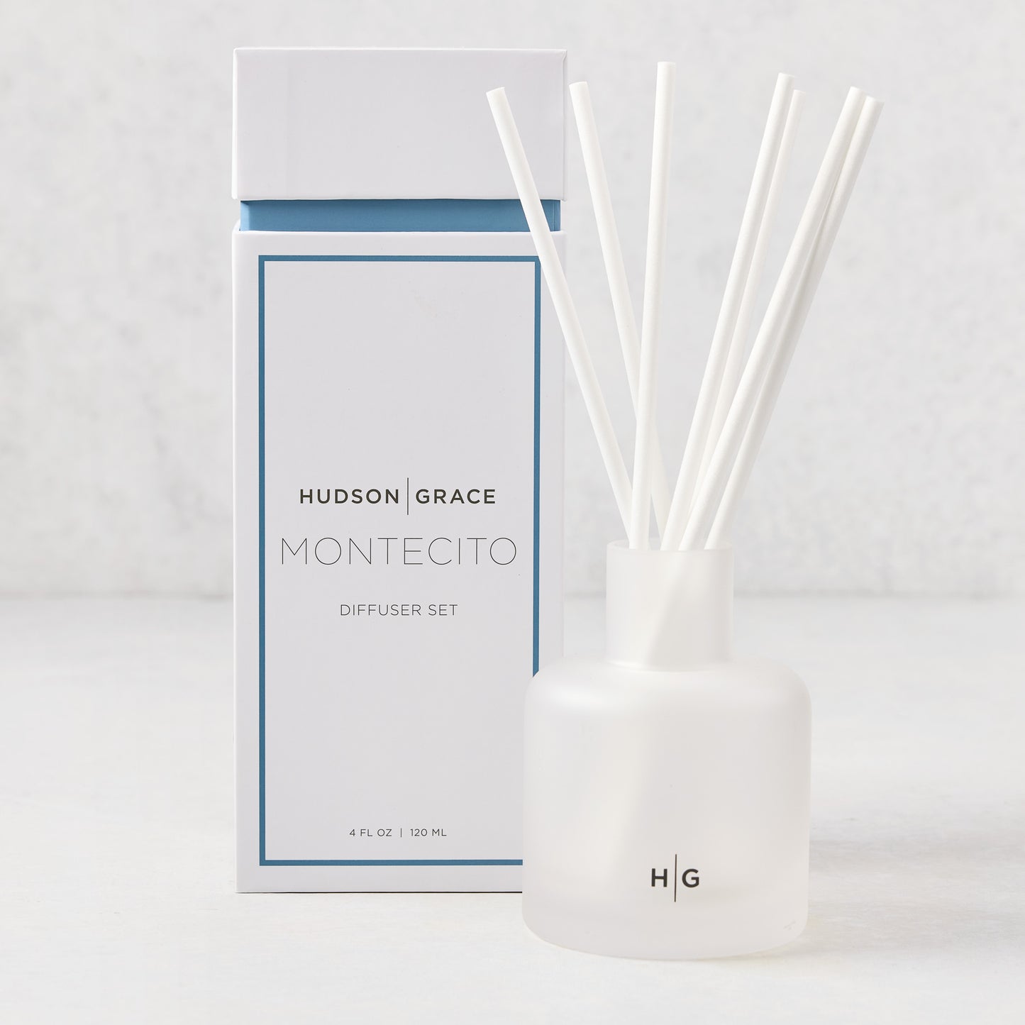 Hudson Grace Montecito Scented Reed Diffuser set with frosted glass vessel, white reeds, and white box.