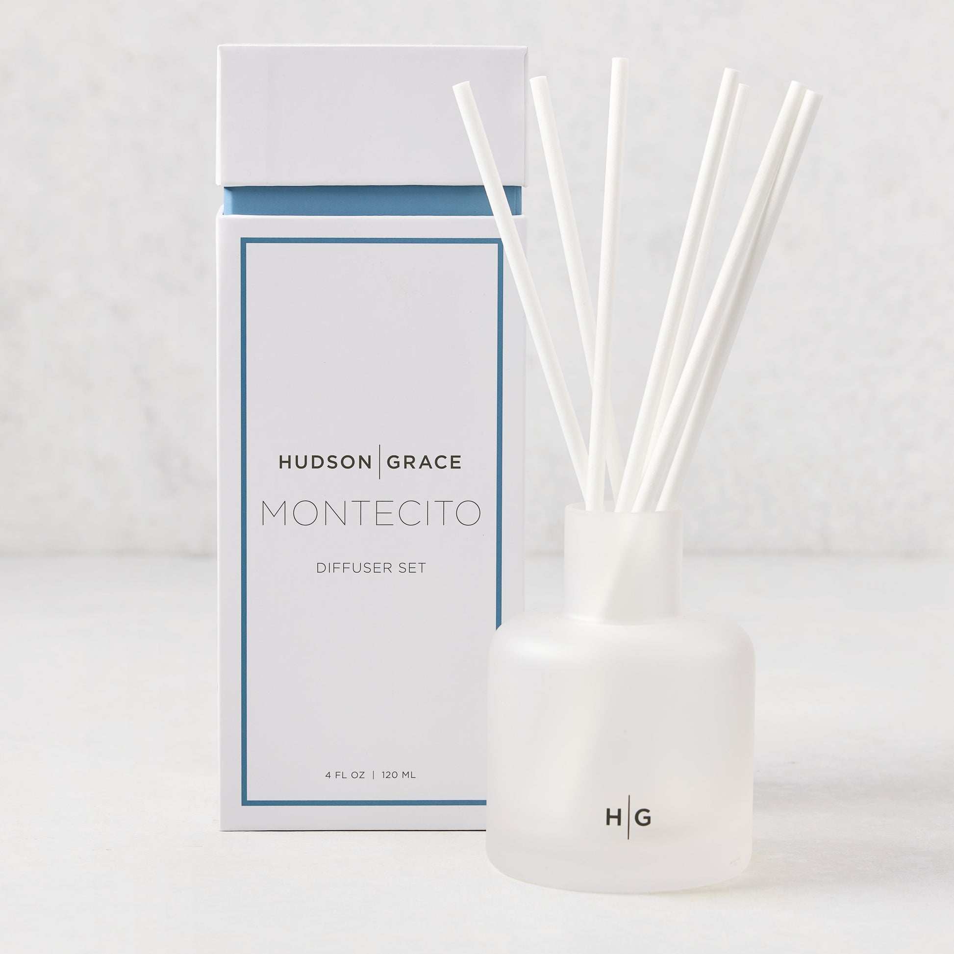 Hudson Grace Montecito Scented Reed Diffuser set with frosted glass vessel, white reeds, and white box.