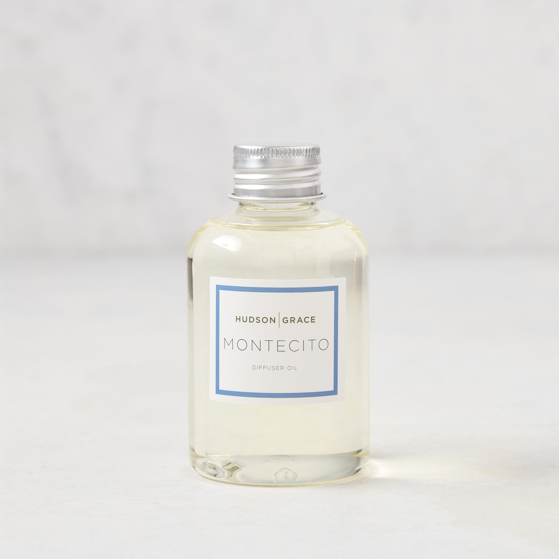 Hudson Grace Montecito 4oz clear glass diffuser oil refill bottle with silver cap and blue label.