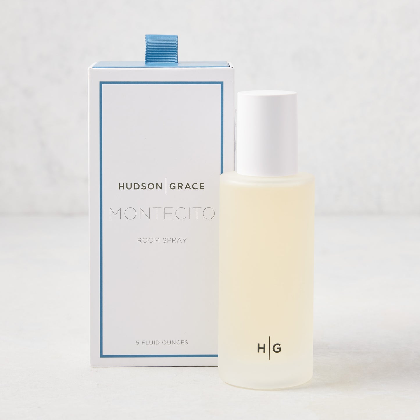 Hudson Grace Montecito 5 oz room spray in a frosted glass bottle with white cap, beside its white and blue box.