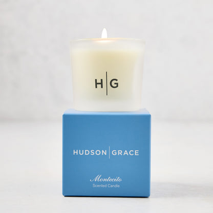 Hudson Grace Montecito scented votive candle in a frosted glass vessel with a blue box.