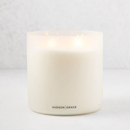 Hudson Grace Original Scented 4-Wick Candle in a white frosted glass vessel, lit.