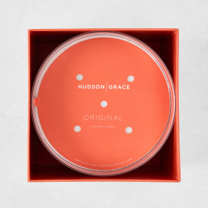 Hudson Grace Original Scented 4-Wick Candle in an orange box, with a clear lid and orange dust cover.