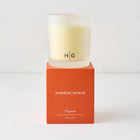 Hudson Grace Original Scented Candle in a frosted glass vessel with "HG" logo, on an orange box.