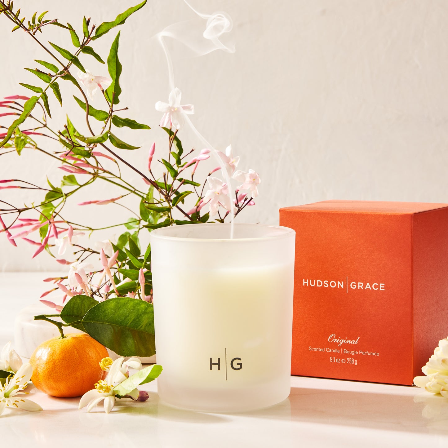 Hudson Grace Original scented candle in a frosted glass jar with an orange box, jasmine, and citrus.