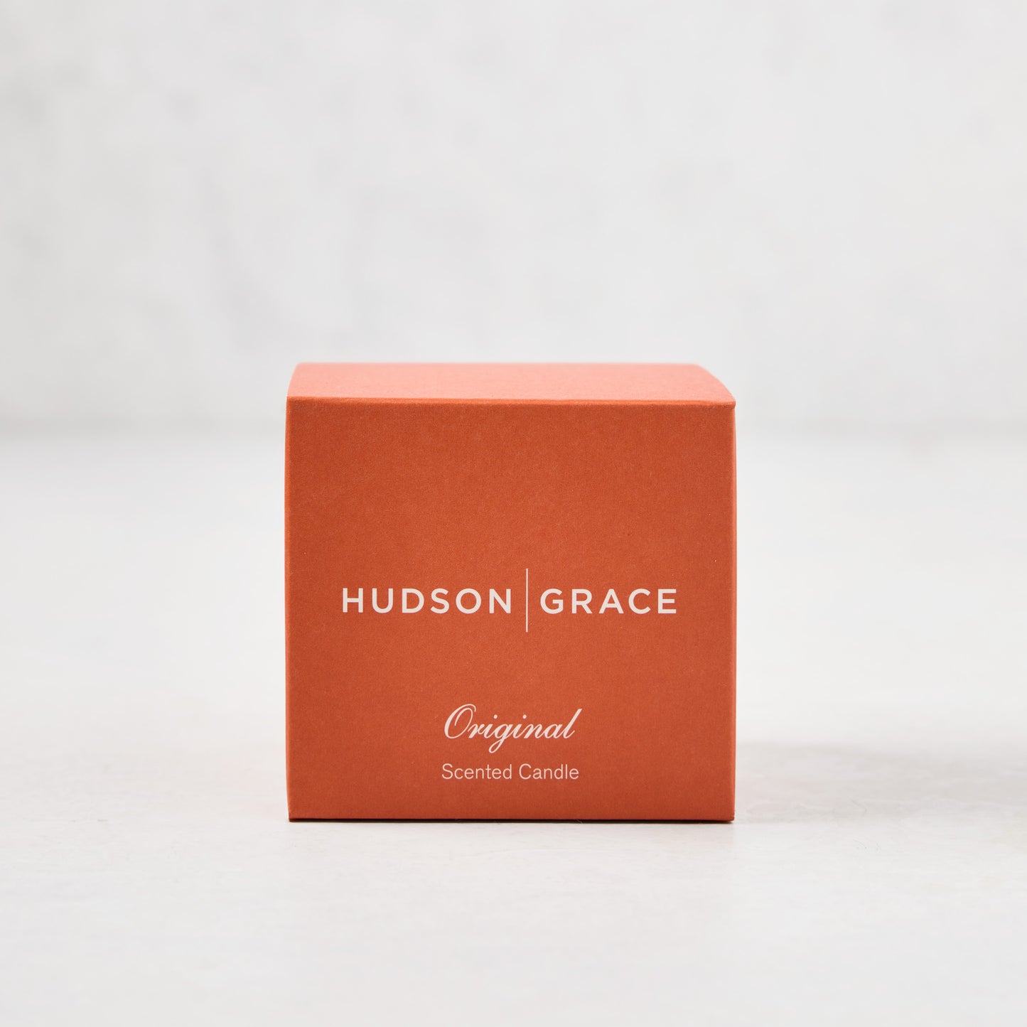 Hudson Grace Original Scented Votive Candle in an orange box with white text.