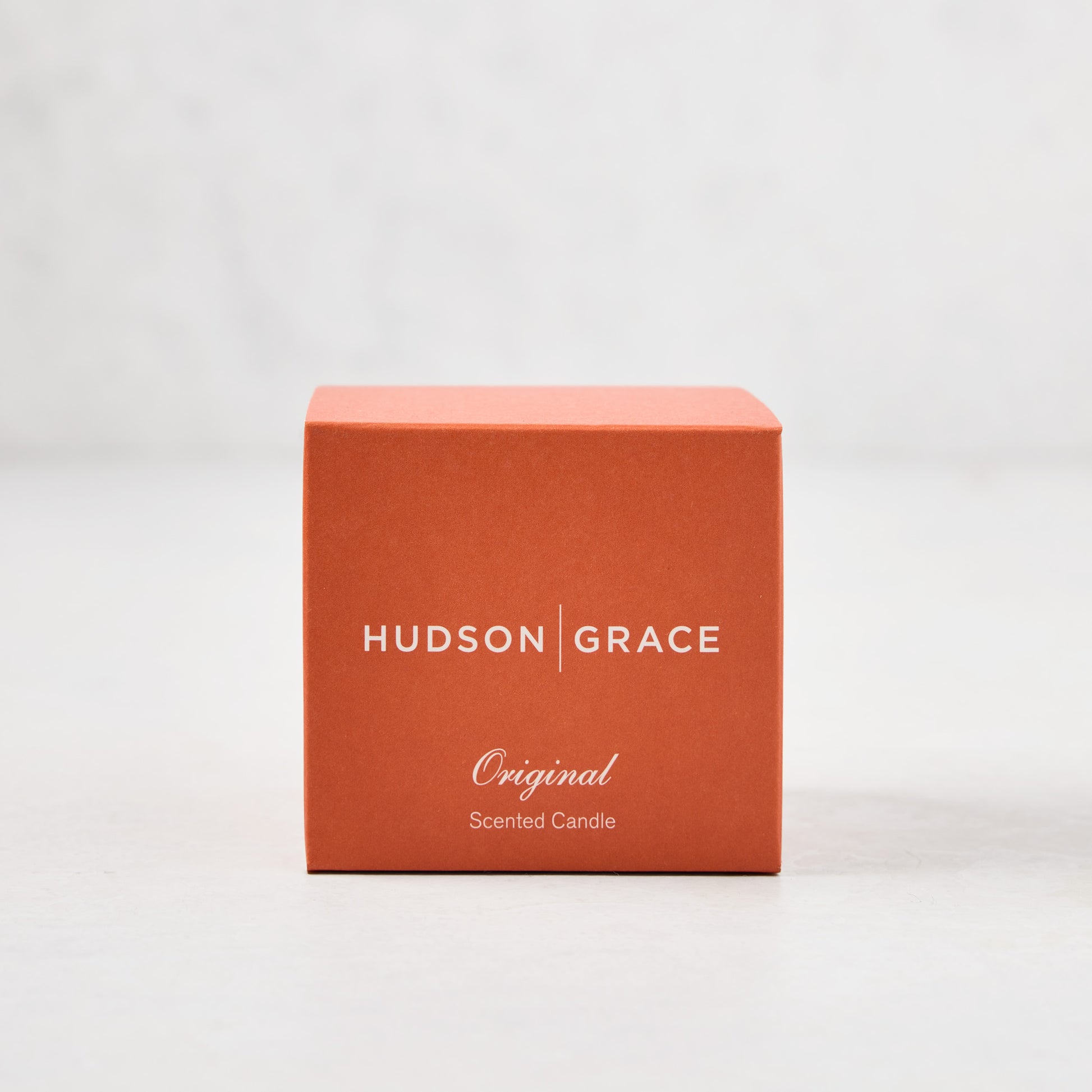 Hudson Grace Original Scented Votive Candle in an orange box with white text.