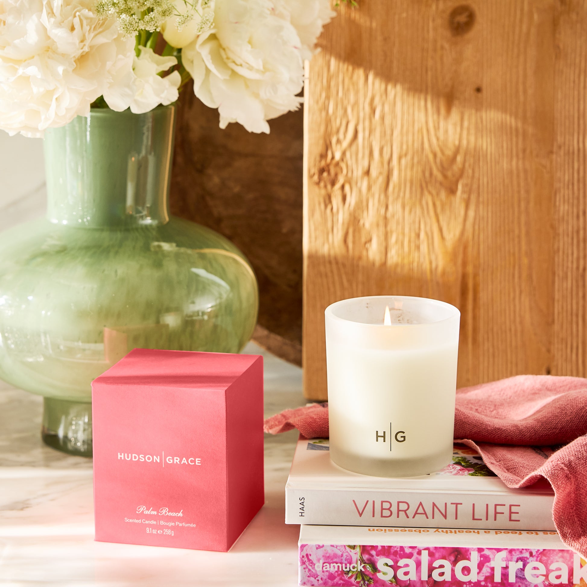 Hudson Grace Palm Beach scented candle in a frosted glass vessel with "HG" logo, next to its pink box.