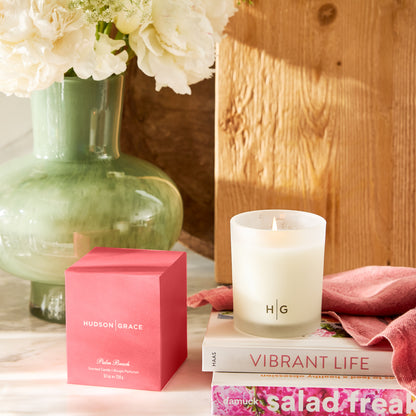 Hudson Grace Palm Beach scented candle in a frosted glass vessel with "HG" logo, next to its pink box.