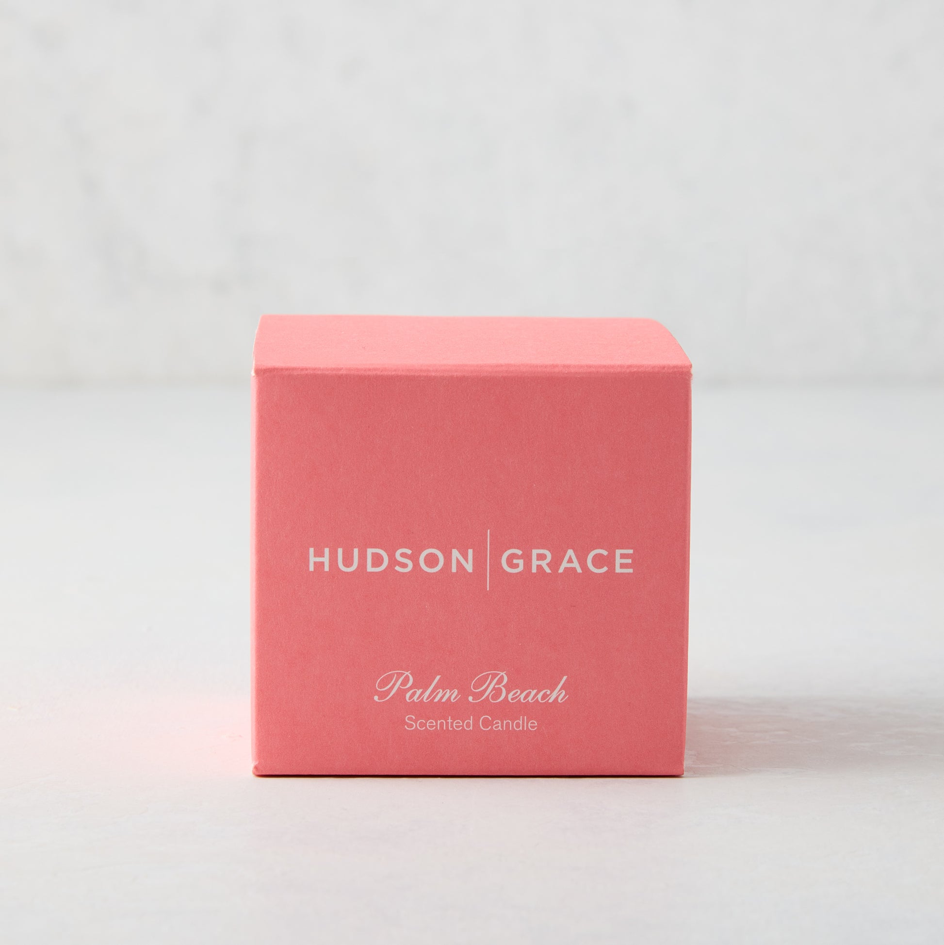 Hudson Grace Palm Beach Scented Votive Candle in a coral pink box with white text.