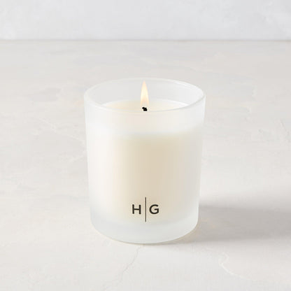 Hudson Grace San Marzano scented candle in a frosted glass vessel with "HG" logo, lit wick.