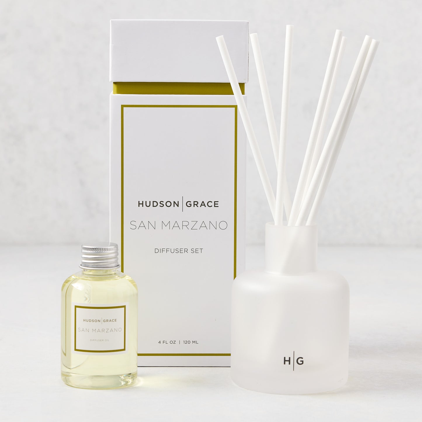 Hudson Grace San Marzano reed diffuser set: frosted glass vessel, white reeds, oil bottle, and white box with gold trim.