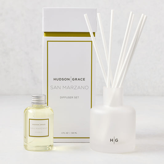 Hudson Grace San Marzano reed diffuser set: frosted glass vessel, white reeds, oil bottle, and white box with gold trim.