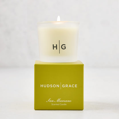 Hudson Grace San Marzano Votive candle in a frosted glass vessel with "HG" logo, atop a green box.