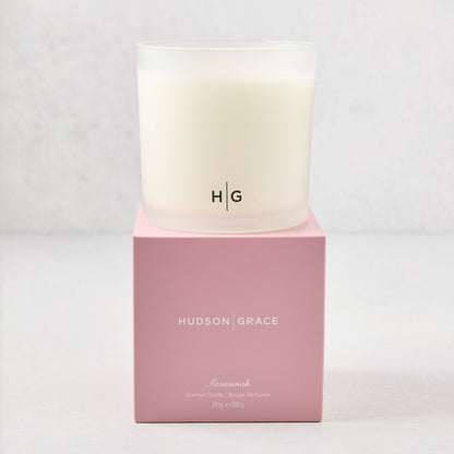Hudson Grace Savannah 3-wick candle in a frosted glass vessel with HG logo, on a pink gift box.