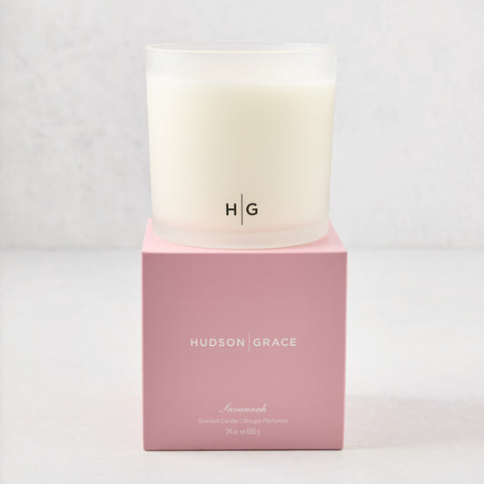 Hudson Grace Savannah 3-wick candle in a frosted glass vessel with HG logo, on a pink gift box.