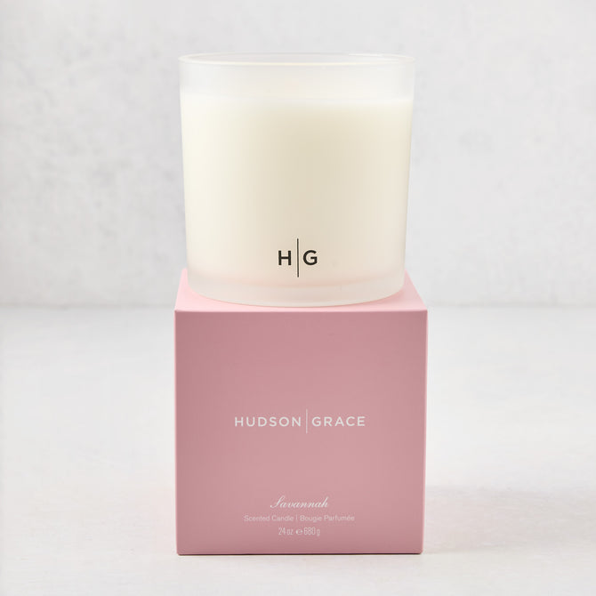 Hudson Grace Savannah 3-wick candle in a frosted glass vessel with HG logo, on a pink gift box.