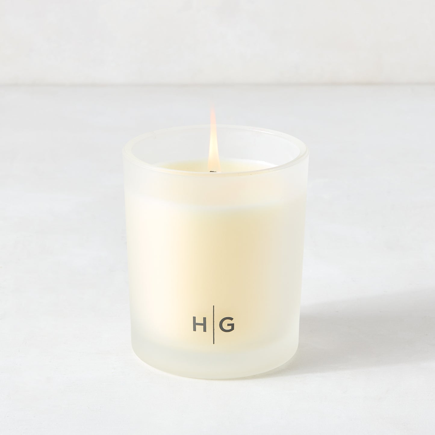 Hudson Grace Savannah scented candle in a frosted glass vessel with a lit wick.