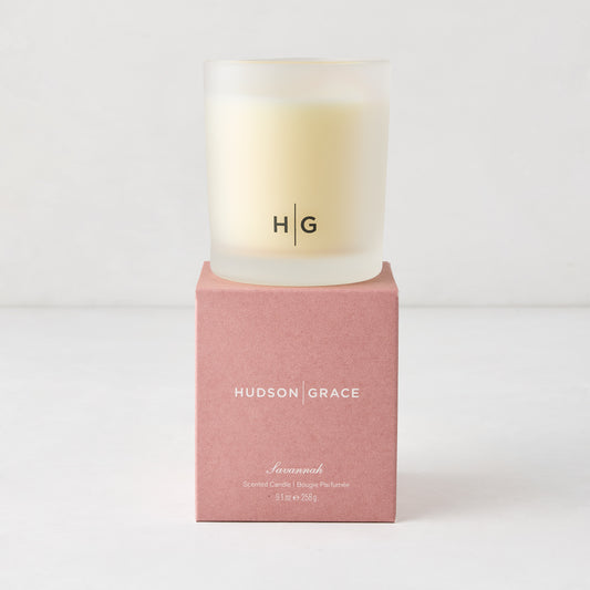 Hudson Grace Savannah scented candle in a frosted glass vessel with HG logo, on a pink box.