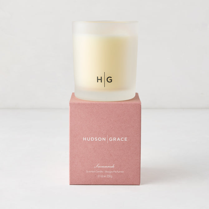 Hudson Grace Savannah scented candle in a frosted glass vessel with HG logo, on a pink box.