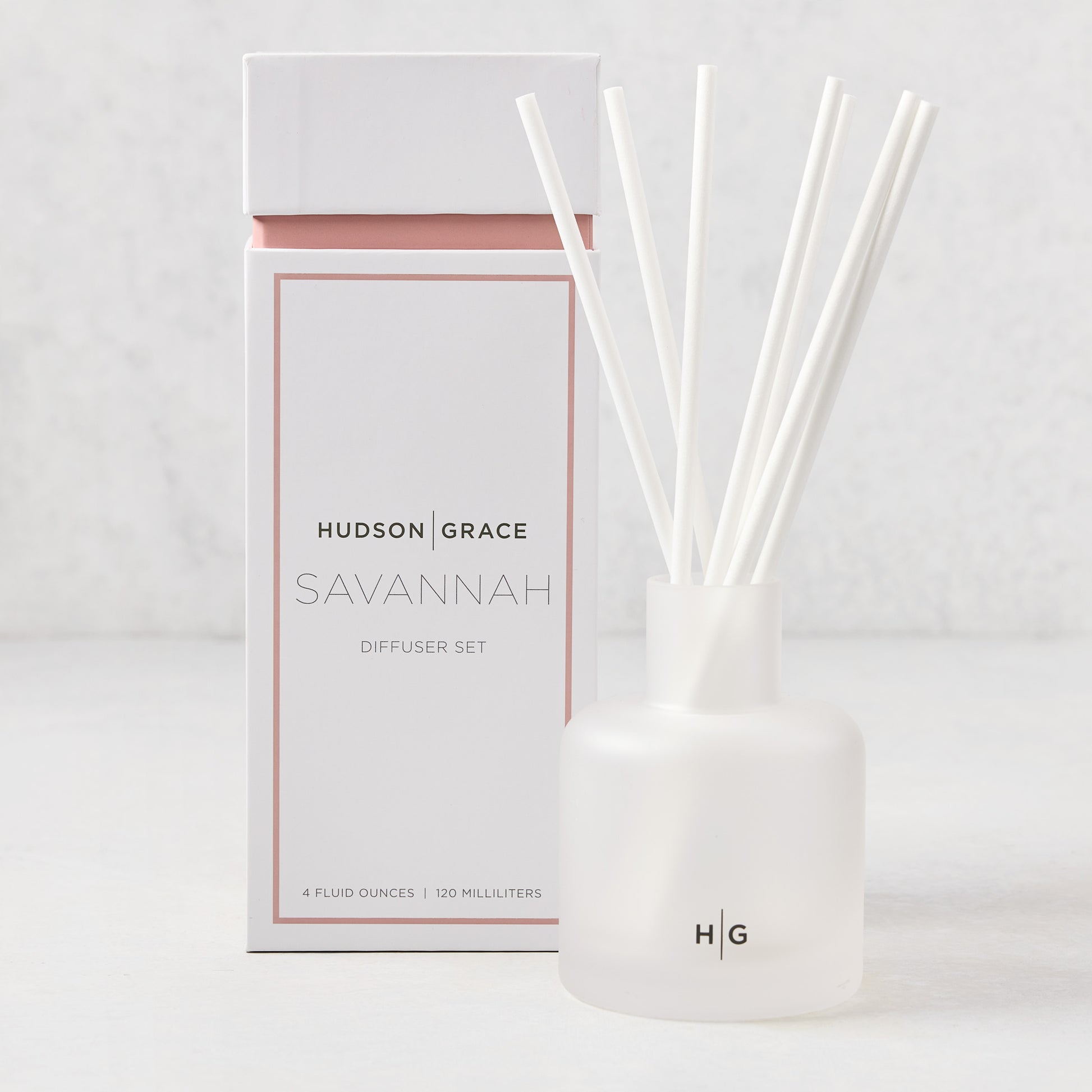 Hudson Grace Savannah Reed Diffuser set with frosted glass vessel, white reeds, and white box with peach accent.