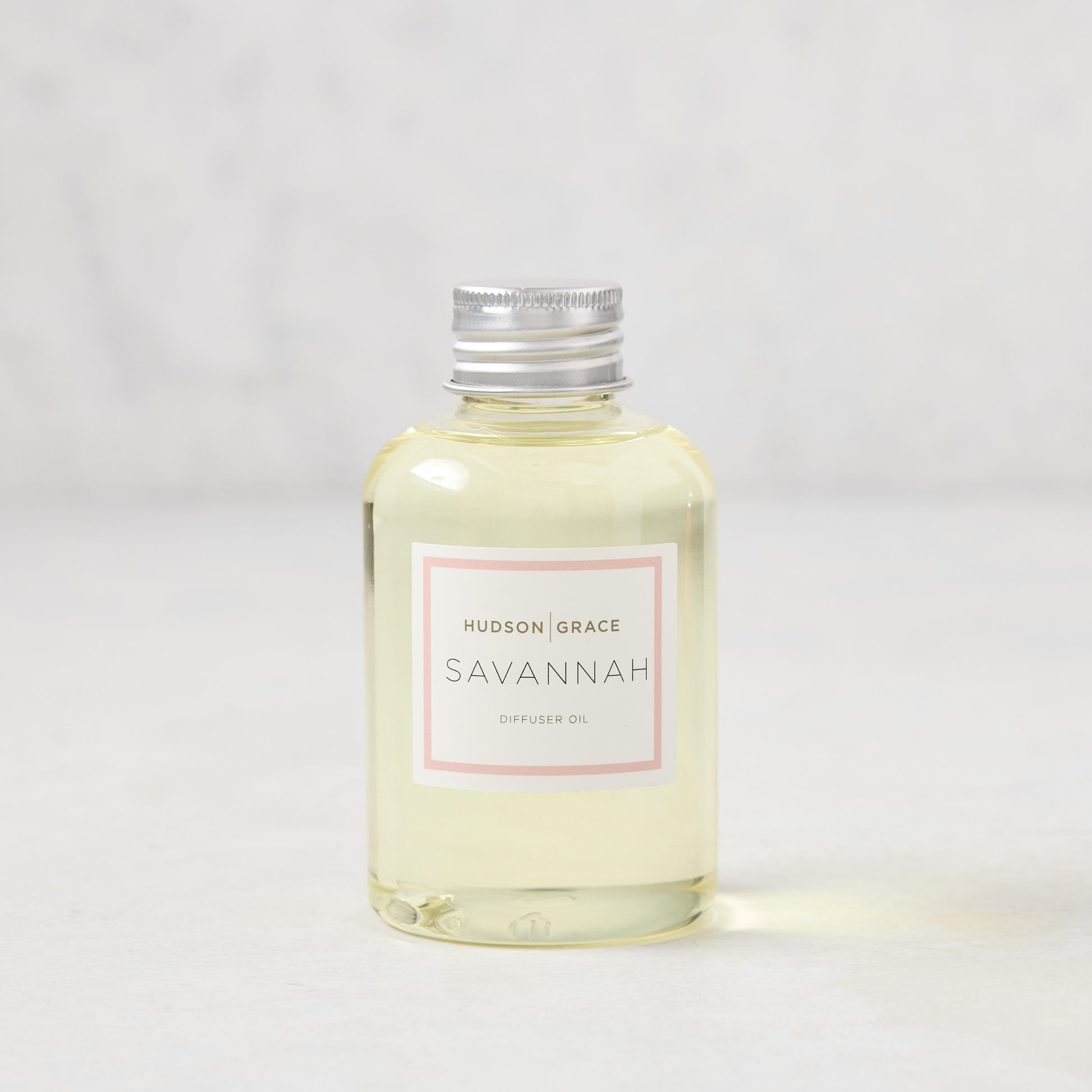 Hudson Grace Savannah scented reed diffuser oil refill, 4oz clear glass bottle with silver cap and pink label.