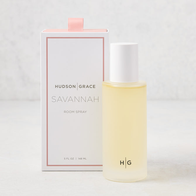 Hudson Grace Savannah Scented Room Spray: 5.08 oz clear glass bottle with white cap next to a white box with pink ribbon.