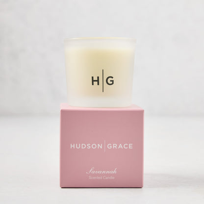 Hudson Grace Savannah Votive Scented Candle in a frosted glass vessel on a pink gift box.