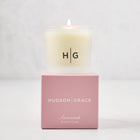 Hudson Grace Savannah Votive Scented Candle in frosted glass vessel with HG logo, on a pink gift box.