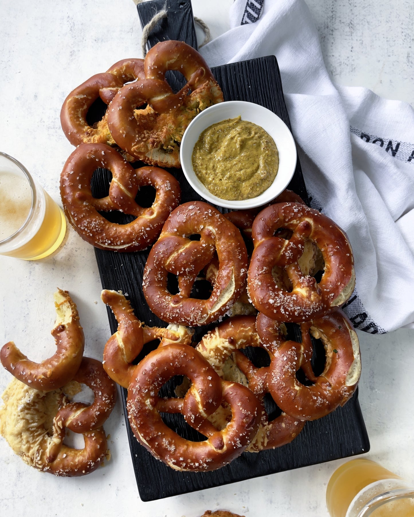 Soft pretzels with mustard and beer served on a black wood board for game day entertaining