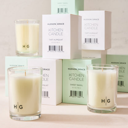 Hudson Grace Sweet Basil Kitchen Candle in a clear glass jar with white wax, alongside white and mint green boxes.