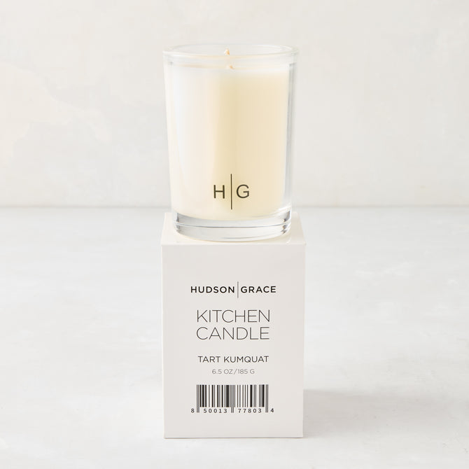 Hudson Grace Tart Kumquat Kitchen Candle in a clear glass votive with HG logo, on its white box.