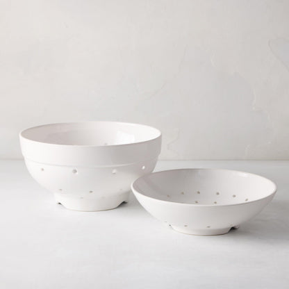 Two white ceramic berry bowls, one large and one small, with drainage holes.