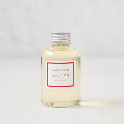 Hudson Grace Winter Scented Reed Diffuser oil bottle, clear glass with silver cap and white label.