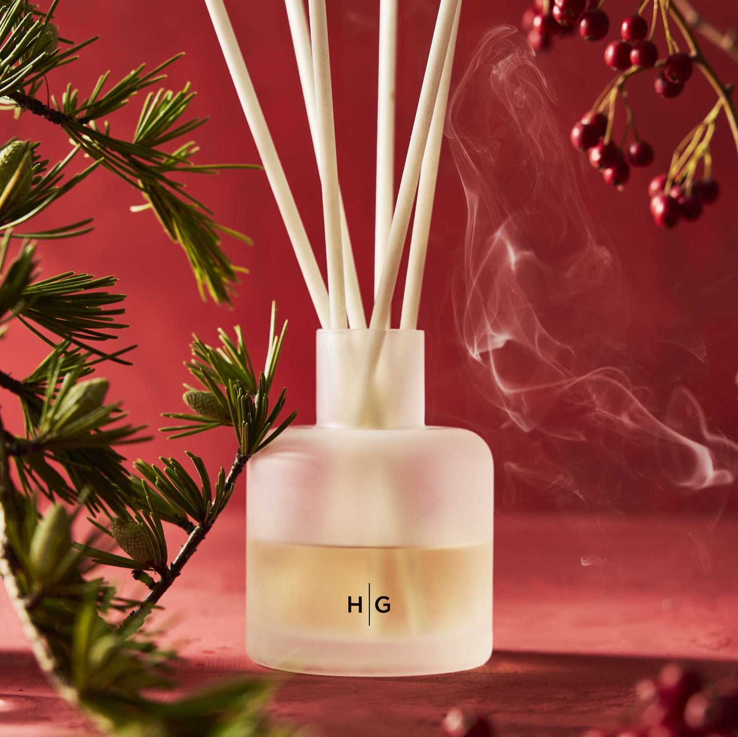Hudson Grace Winter Scented Room Spray in a frosted glass bottle with white reeds, pine, and red berries.