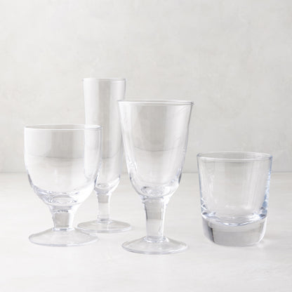 Clear glass stemless and stemmed glasses, including a chunky Hudson glass, on a white surface.