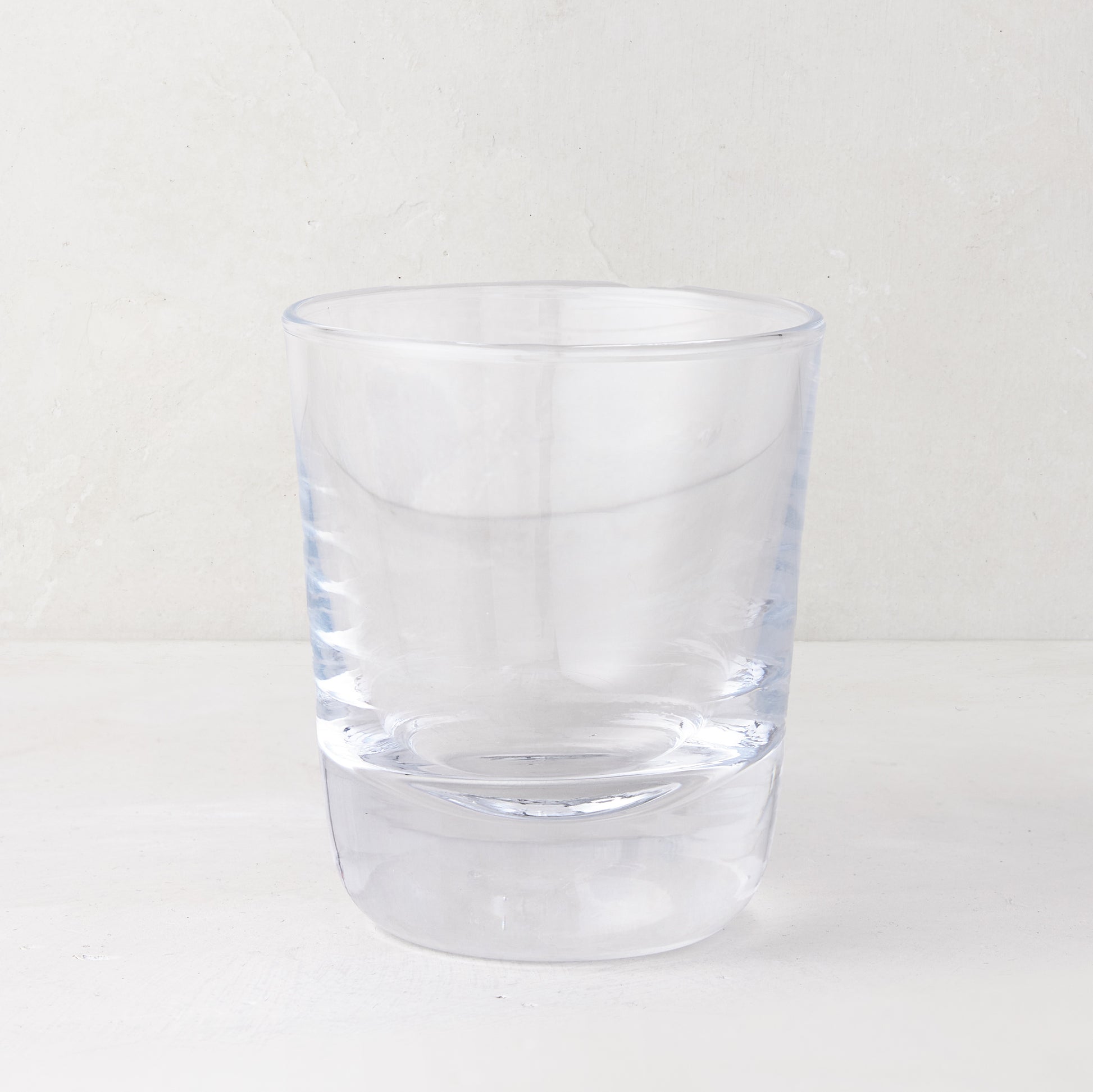 Clear, chunky Hudson Stemless Glass, 3.5"Dia x 4"H, with a thick base, on a white surface.
