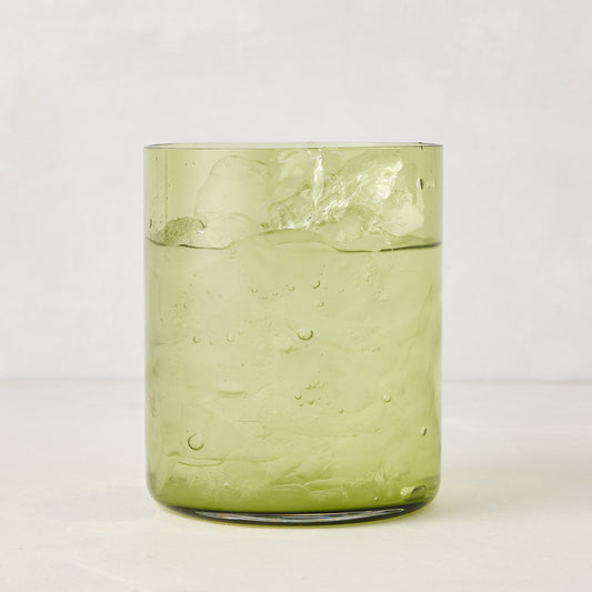 Hugo Aloe Green Double Old Fashioned Glass, filled with ice and a clear drink. Handmade glass, 3.25"Dia x 4"H.