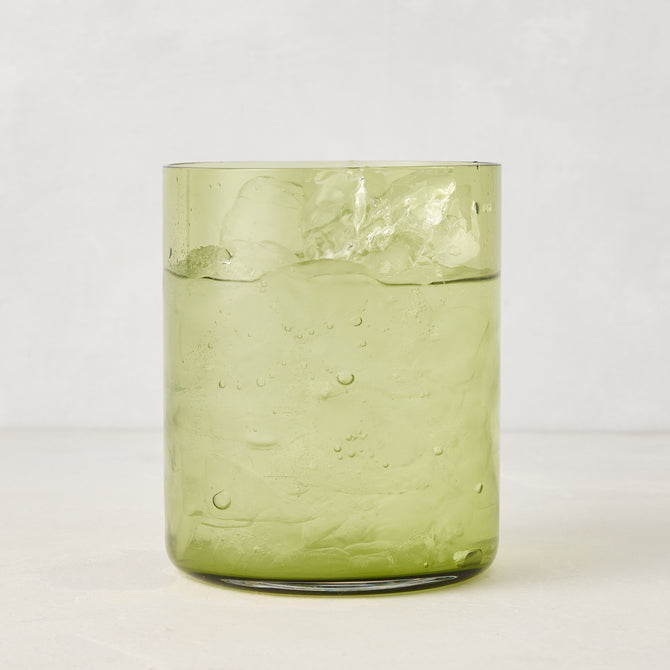 Hugo Aloe Green Double Old Fashioned Glass, filled with ice and a clear drink. Handmade glass, 3.25"Dia x 4"H.