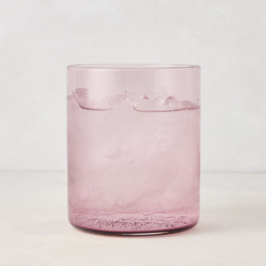 Hugo Fig Double Old Fashioned Glass, a sleek, sturdy pink glass with ice and a sparkling drink.