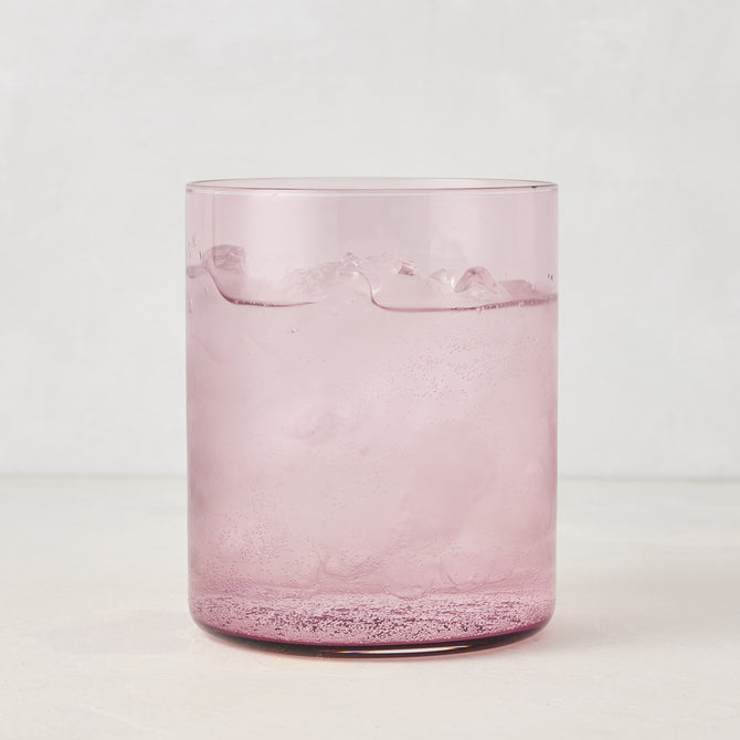 Hugo Fig Double Old Fashioned Glass, a sleek, sturdy pink glass with ice and a sparkling drink.