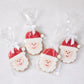 Set of four oversized sugar cookies shaped like Santa Claus, decorated with red and white icing, individually wrapped with white bows.