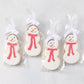 Set of four oversized snowman-shaped sugar cookies with white icing, orange carrot noses, and red polka-dot scarves in bags.