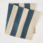 Folded Indigo Blue Hampton Stripe Natural Cotton Napkin, 22" square, with wide blue and khaki stripes.