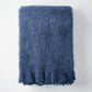 Folded indigo blue mohair throw blanket with a soft, shaggy texture.