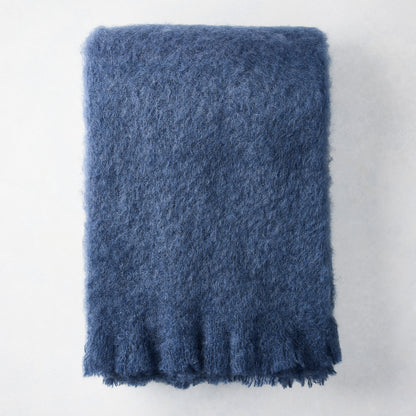 Folded indigo blue mohair throw blanket with a soft, shaggy texture.