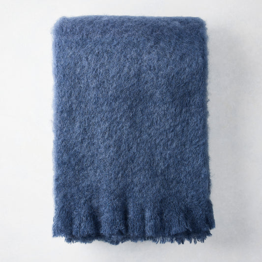 Folded indigo blue mohair throw blanket with a soft, shaggy texture.